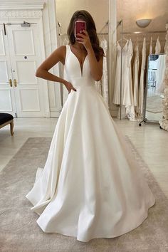 a woman taking a selfie in her wedding dress while looking at her cell phone