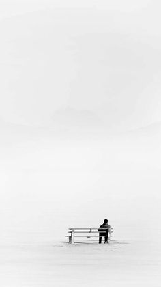 a man sitting on top of a bench in the snow