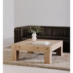 a living room with a couch, coffee table and rug on the floor in front of it