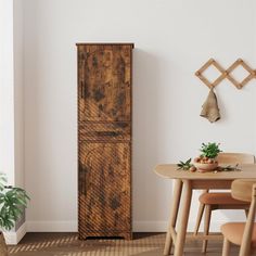 a wooden cabinet sitting in the corner of a room next to a table and chairs