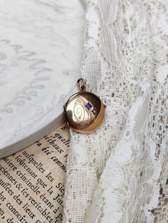 "Beautiful antique gold-plated locket, with a small blue paste stone and a small pearl.  The locket is in overall good antique condition, with some traces of wear and age, consistent with the age of the jewel.  The locket is engraved on the back with a name: \"M Metzger Gonten\". Dimensions: approx. 2.1 x 2.9 cm. Diameter: approx. 2.1 cm.  Colour variations may occur due to the light. The exact colour of the jewel does not come out perfectly in all the photos." Blue Victorian Jewelry With Vintage Charm, Vintage Blue Necklace With Pearl Pendant, Antique Blue Locket Jewelry, Victorian Blue Locket Jewelry, Blue Victorian Locket Jewelry, Locket Gold, Gold Locket, The Jewel, Locket Necklace