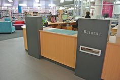 an empty library with people sitting at the desks and bookshelves in the background