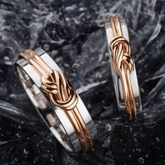 two gold and silver rings with an intertwined knot on each ring, sitting on black marble