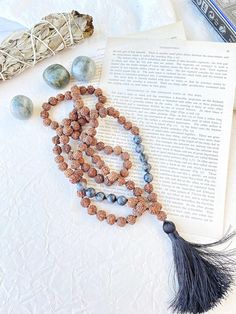 "Natural Rudraksha seeds and labradorite mala garland for meditation made by hand for me. 108 knotted bead garland for counting mantras.  With these seeds, traditionally used to pray in Hinduism and Buddhism, malas or Hindu rosary are made, which must have 108 beads (a \"magic\" number in Hinduism).  But they are also widely used in traditional Indian medicine for their supposed healing properties. In this mala we combine the mystique of rudraksha seeds with different stones that complement each other, resulting in very special jewels  I make each mala by hand, knotting each of the 108 beads with great care and I made every single silky and delicate tassel. I use a very resistant braided macrame rope, achieving a mala that lasts over time. This sacred mala necklace has 108 knotted beads of Hand Wrapped Mala For Meditation, Hand Wrapped Mala With Round Beads For Meditation, Hand Wrapped Round Beads Mala For Meditation, Holistic Mala With 108 Beads For Festival, Spiritual Healing Mala With Round Beads, Holistic Hand Knotted Jewelry Gift, Holistic Handmade Jewelry For Yoga, Adjustable Spiritual Hand-strung Mala, Adjustable Hand-strung Spiritual Mala