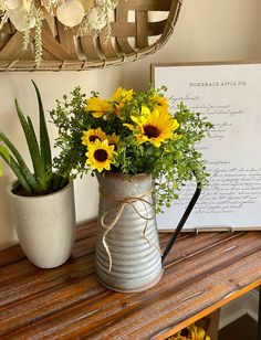 two vases with yellow flowers are sitting on a wooden table next to a sign