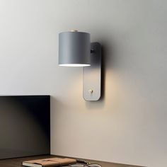 a lamp that is on the side of a wall next to a book and cell phone