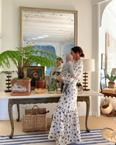 a woman standing in front of a mirror holding a baby