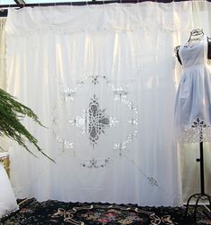 a white curtain is hanging next to a dress on a mannequin's dummy