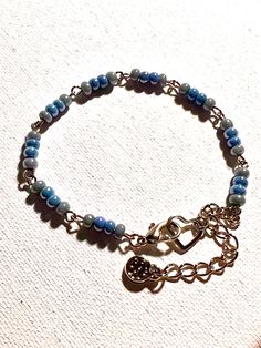 Pretty dainty sky blue glass seed bead bracelet, with lobster claw clasp. Also includes textured charm. This bracelet is made by linking together beaded wire creating a unique look. Great gift for your friend, wife, daughter, or anyone special in your life. Adjustable; fits 6.5-7.5 inch wrist, clip the clasp to heart or on any link for convenient adjustment. Two additional days needed for any special requests. Message me for more info. Dainty Blue Round Bead Bracelets, Handmade Adjustable Czech Glass Charm Bracelet, Dainty Adjustable Wire Wrapped Beaded Bracelets, Blue Jewelry With Tiny Beads For Everyday, Everyday Blue Jewelry With Tiny Beads, Dainty Blue Beaded Chain Bracelet, Adjustable Blue Wire Wrapped Beaded Bracelets, Handmade Blue Charm Bracelet For Friendship, Metal Beaded Bracelets With Round Beads