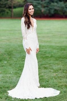 a woman in a wedding dress standing on the grass