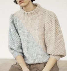 a woman sitting on top of a wooden floor wearing a sweater