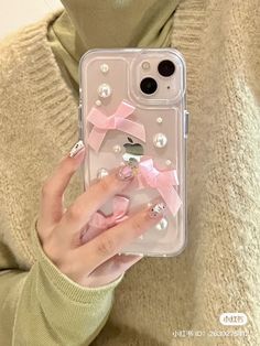 a woman is holding up her phone case with pink bows and pearls on the back