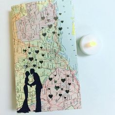 a couple holding hands in front of a map with hearts on it next to a candle