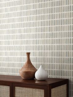 two vases sit on top of a wooden shelf in front of a wallpapered background