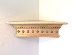 a wooden shelf mounted to the side of a white wall with holes in between it