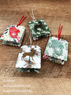 four christmas ornaments on a wooden table with red and green tags hanging from the top