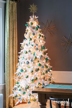 a white christmas tree with green and gold ornaments