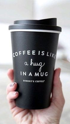 a person holding a coffee cup with the words coffee is like a hug in a mug