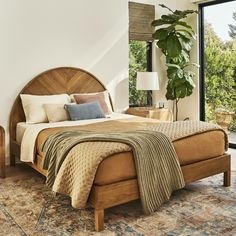 a bedroom with a bed, nightstands and plants in the window sill next to it