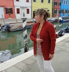 a woman standing next to a body of water with boats in the backgroud