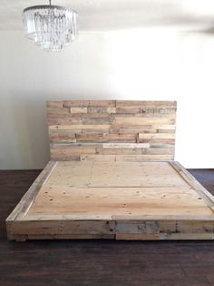 a bed made out of pallet wood with a chandelier hanging from the ceiling