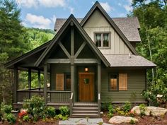 a house in the woods with lots of trees and bushes on the front lawn, along with steps leading up to the front door