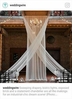 an indoor wedding venue with white draping and chandeliers