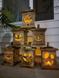 a group of wooden boxes with carved pumpkin faces on them, sitting in front of a house