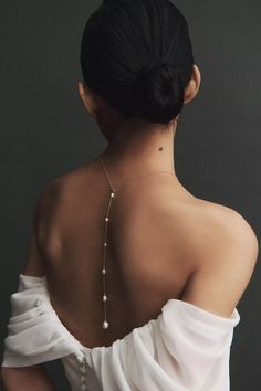 a woman wearing a white dress with pearls on her back