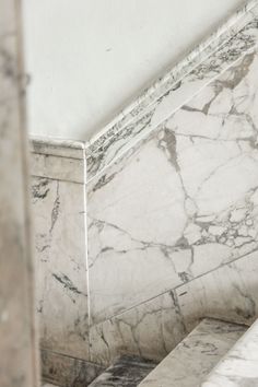 a marbled wall and floor in a room with white walls, stairs and tile