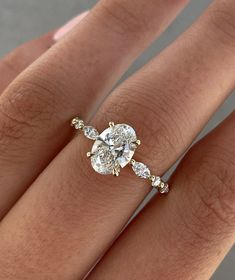 a woman's hand with a diamond ring on top of her finger and an engagement band