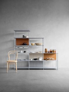 a chair sitting in front of a shelf filled with plates and bowls on top of it