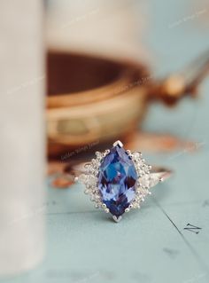 a blue and white diamond ring sitting on top of a table next to a bowl