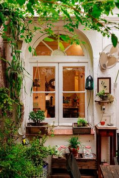 an outside view of a house with potted plants on the window sill and wooden benches