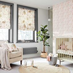 a living room filled with furniture and a baby crib in front of two windows