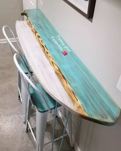 an ironing board sitting on top of two stools next to a table with writing on it