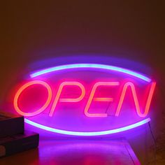 an open sign is lit up in the dark with neon lights on it's sides