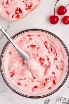 a bowl filled with ice cream and cherries next to two slices of bread on a table