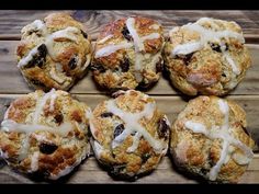 six muffins with icing sitting on top of a wooden table