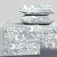 three pillows are stacked on top of each other in front of a white and gray bed