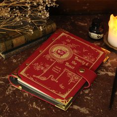 a red book sitting on top of a table next to a candle