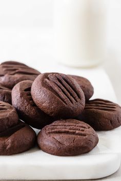 chocolate cookies on a white plate with a glass of milk in the backround