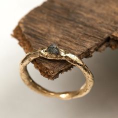 a gold ring with a stone embedded in it sitting on top of a piece of wood