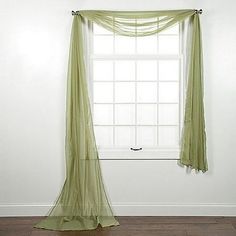 an empty room with a window and sheer curtains