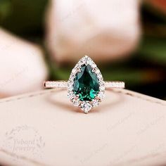 an engagement ring with a pear shaped green diamond