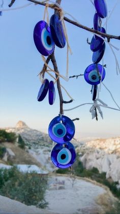 blue glass beads hanging from a tree branch with mountains in the backgroung