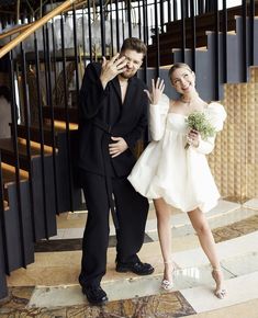 a man standing next to a woman in a white dress on her cell phone while holding a bouquet