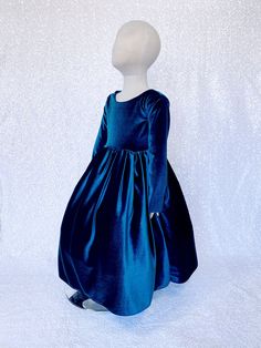 a mannequin wearing a blue velvet dress on a white background in front of a white backdrop