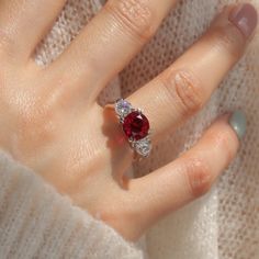 a woman's hand with a ring on it and a red stone in the middle