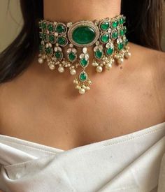 Inspired by the opulent designs of Sabyasachi, this emerald green Victorian choker set is the epitome of elegance and timeless beauty. The choker, meticulously crafted, features a central emerald stone surrounded by intricate gold filigree work that echoes the grandeur of the Victorian era. Each detail is a testament to the exquisite craftsmanship, with tiny pearls and delicate gold beads enhancing the necklace's regal appeal. Complementing the choker are a pair of matching earrings that mirror Indian Choker Necklace Set, Ambani Wedding, Victorian Choker, Unique Wedding Jewelry, Indian Choker, Indian Choker Necklace, Neck Pieces Jewelry, Choker Necklace Designs, Sabyasachi Jewellery